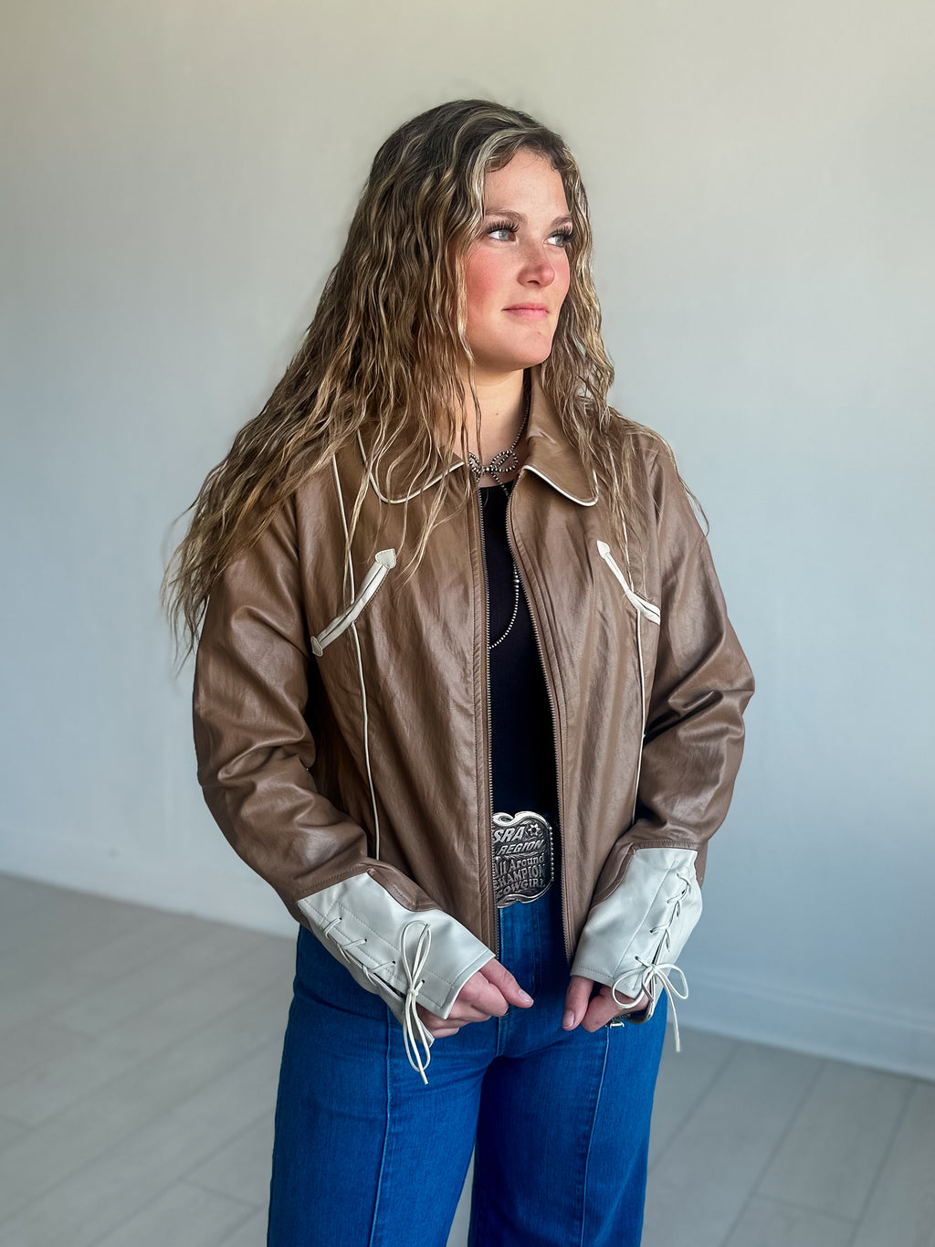 A faux leather brown zip up jacket with western inspired detailing.