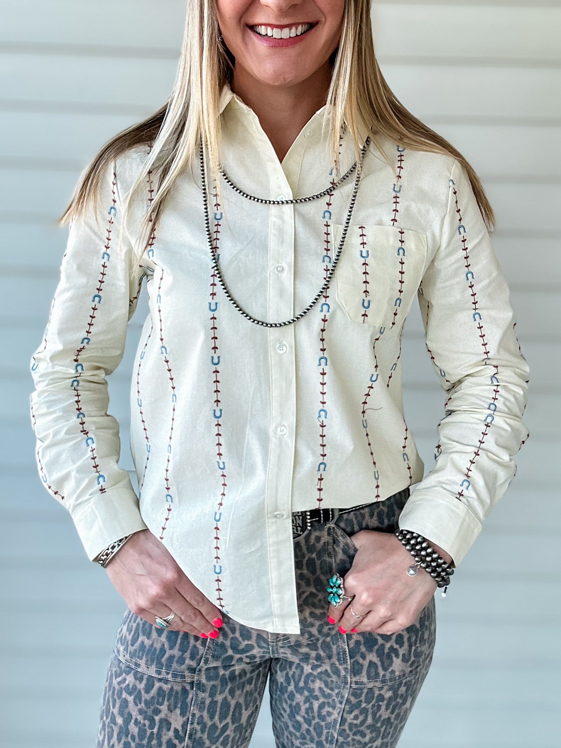 Cream colored button up shirt with embroidered pattern featuring horseshoes and arrows
