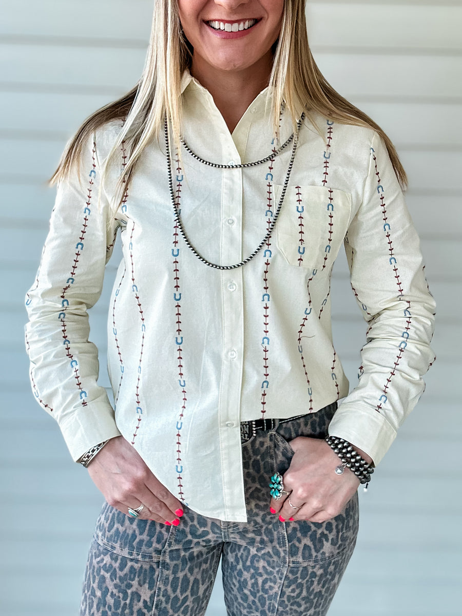 Cream colored button up shirt with embroidered pattern featuring horseshoes and arrows