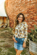 A neautral long sleeve top that features a vintage western pattern.