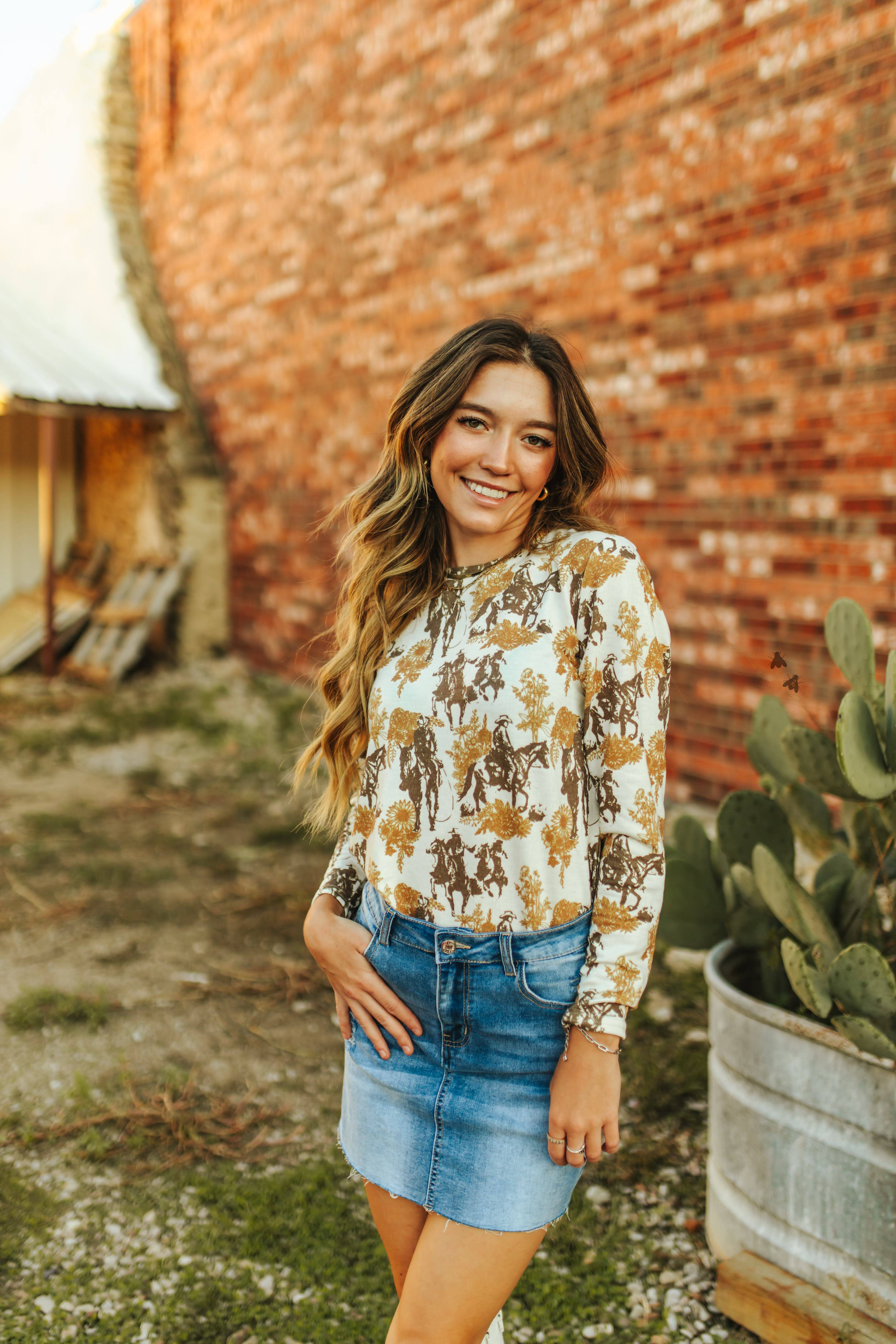 A neautral long sleeve top that features a vintage western pattern.