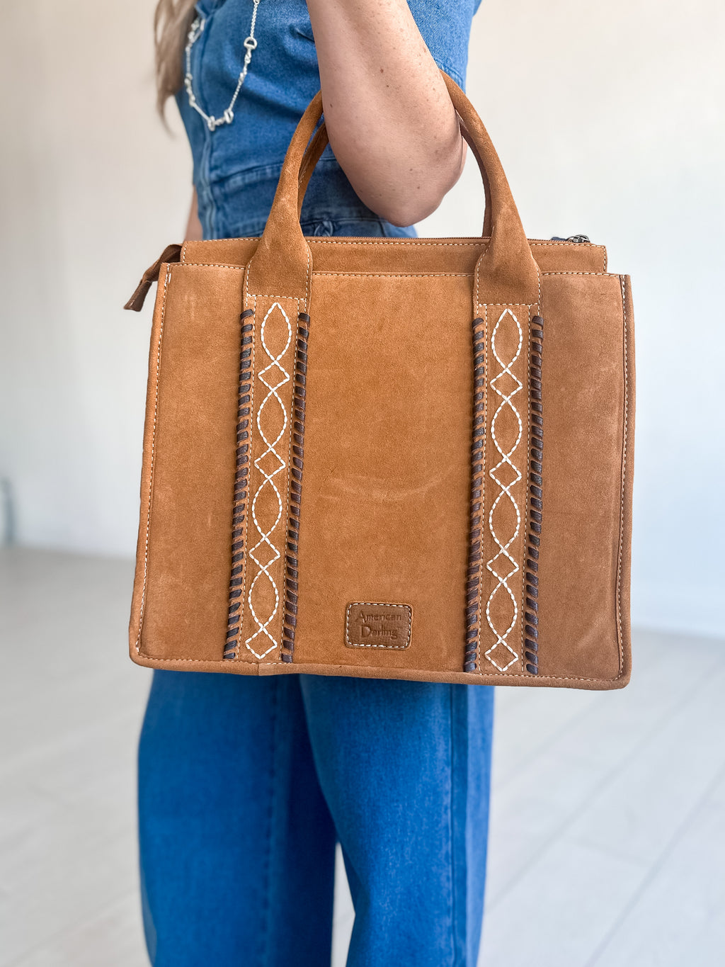 Genuine suede leather tote bag with zipper closures and decorative stitching.