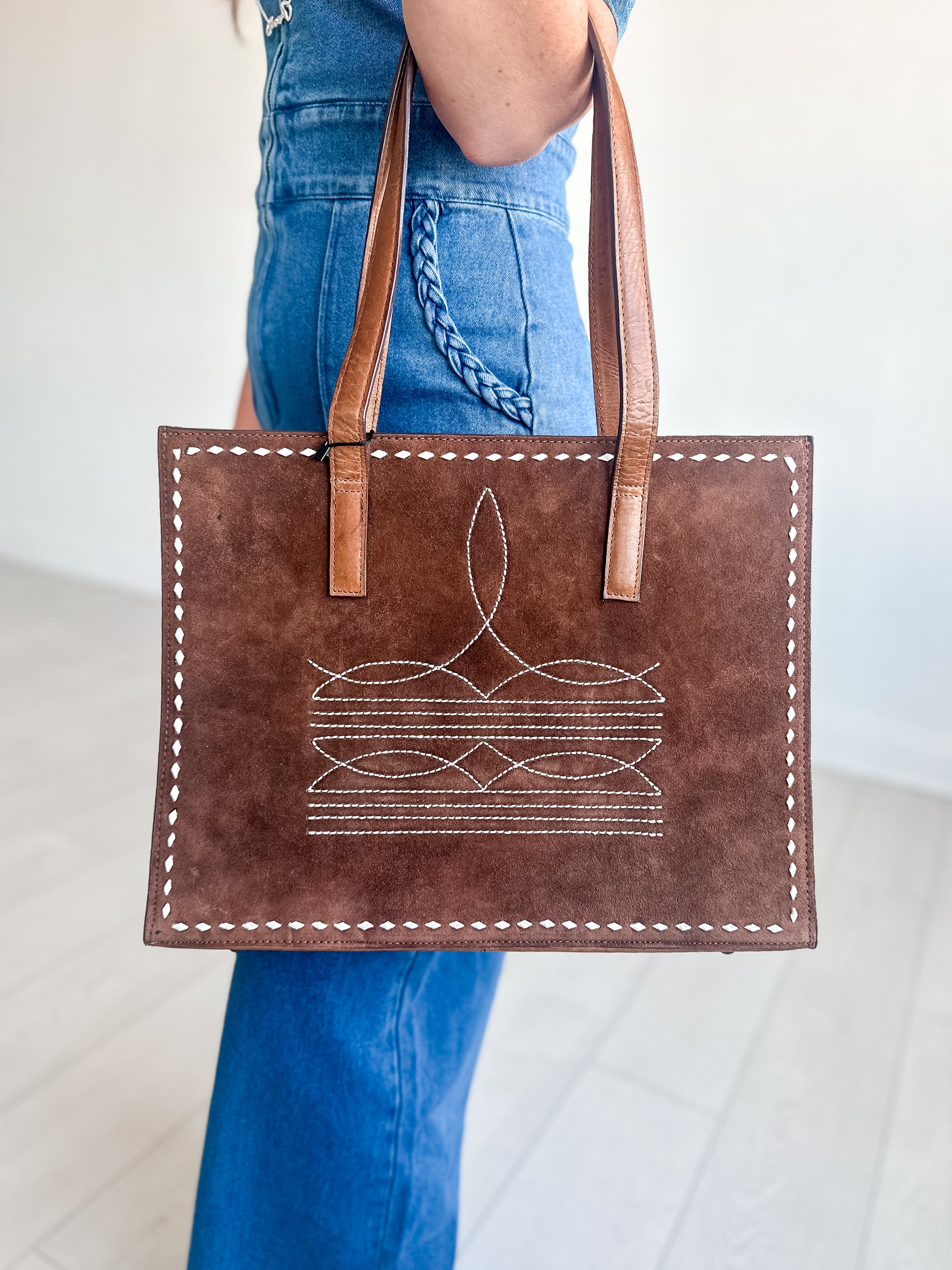 Brown suede tote bag with white stitching  on the front