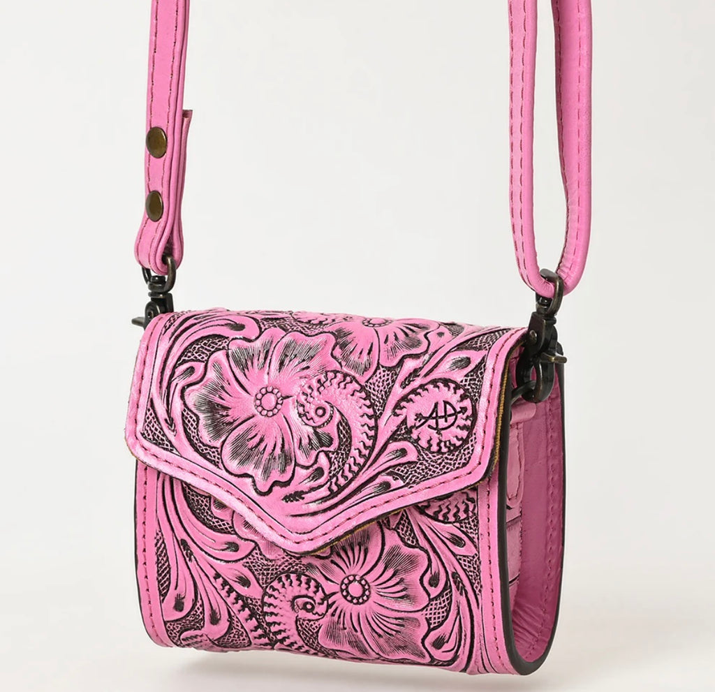 A small pink leather purse with floral hand-tooled patterns and metal fittings.