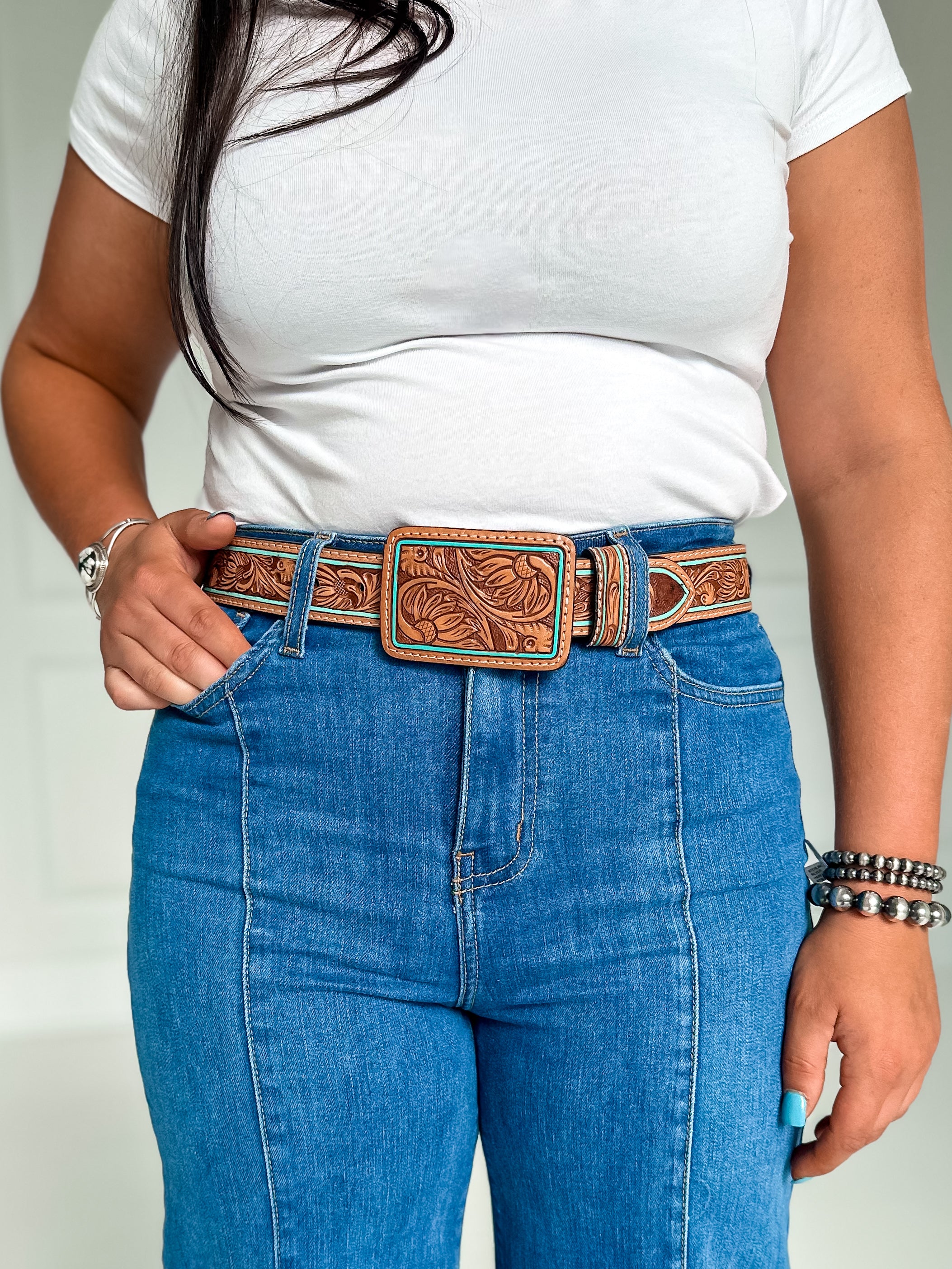 Tooled leather brown belt with floral design and  tooled leather buckle.