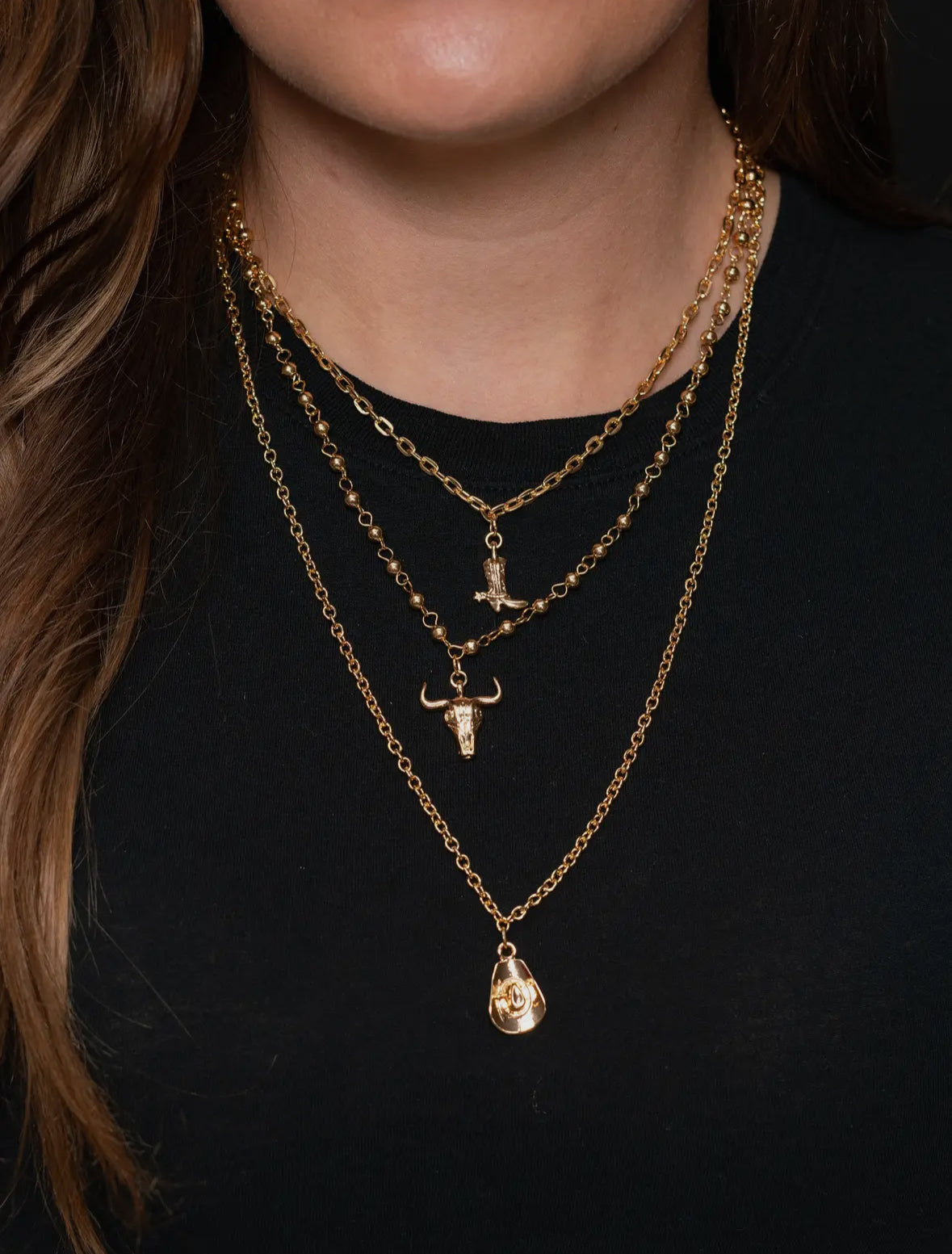 A layered gold necklace with western charms