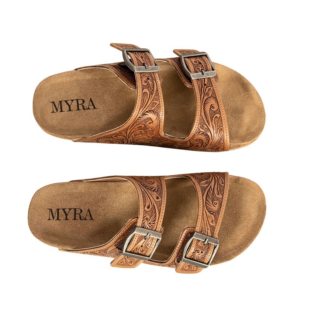 A pair of brown, tooled leather sandals with a floral design and buckle straps, branded with 'MYRA' on the insole.