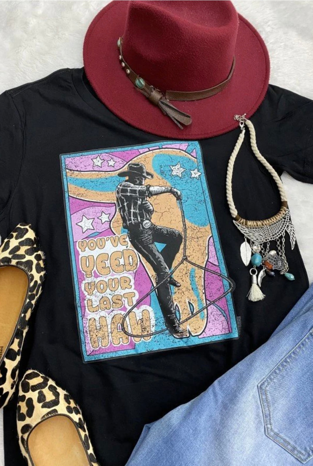 Black women’s short sleeve graphic tee that reads “You’ve Yeed Your Last Haw” with a colorful graphic of a cowboy jumping through a lasso loop.