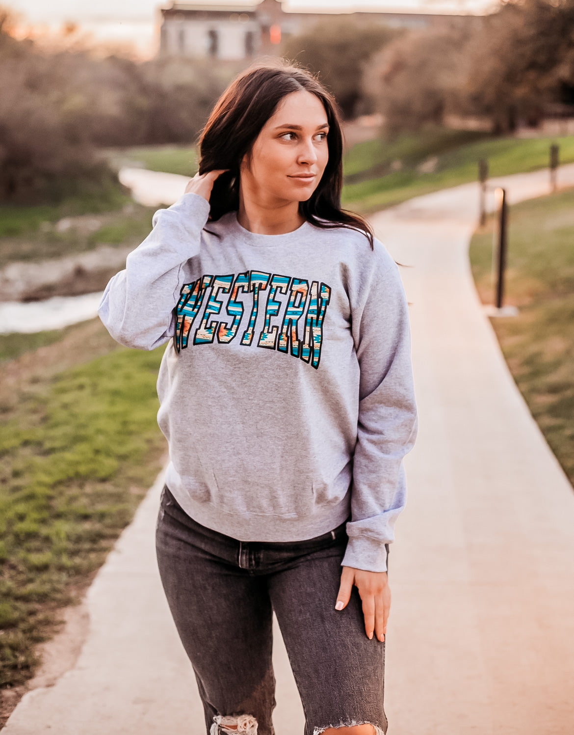 Heather grey crewneck sweatshirt with text WESTERN across front in bright colored aztec pattern